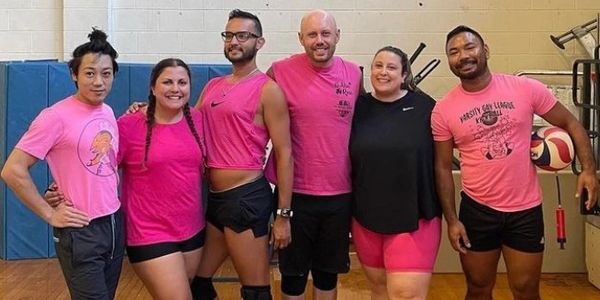 volleyball team smiling taking group photo all wearing pink 
