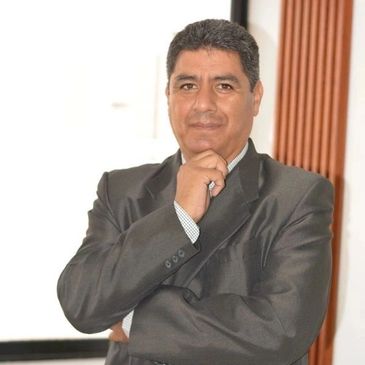 Man in a dark suit posing thoughtfully with hand on chin.