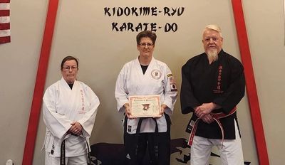 Three karate practitioners pose in front of a Kidokime-Ryu Karate-Do sign.
