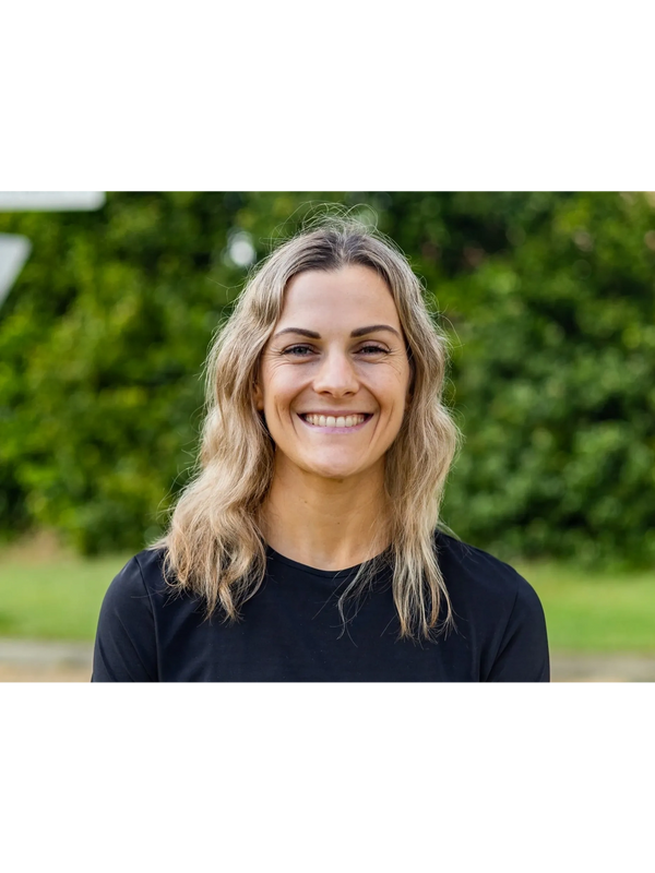 Smiling woman with blonde hair wearing a black shirt outdoors.