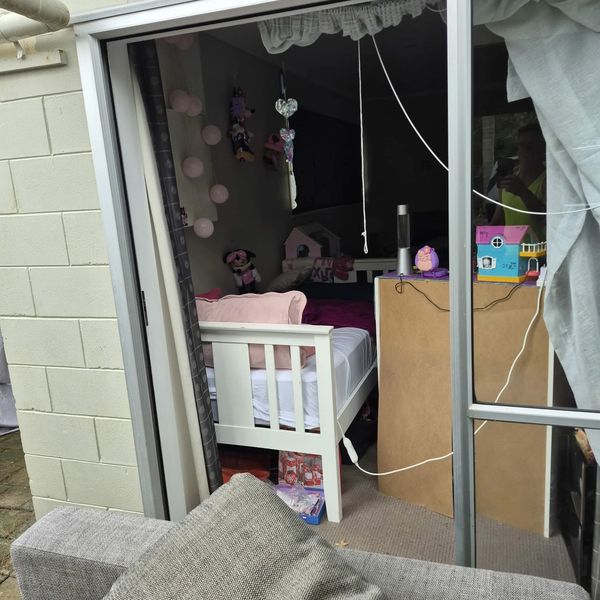 View through a glass door into a cozy child's bedroom with toys and bed.