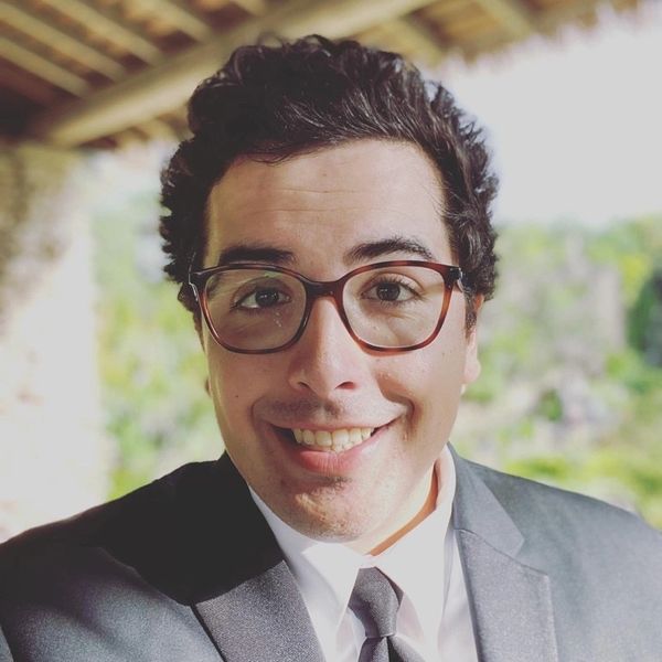 Man in a suit and glasses smiling.