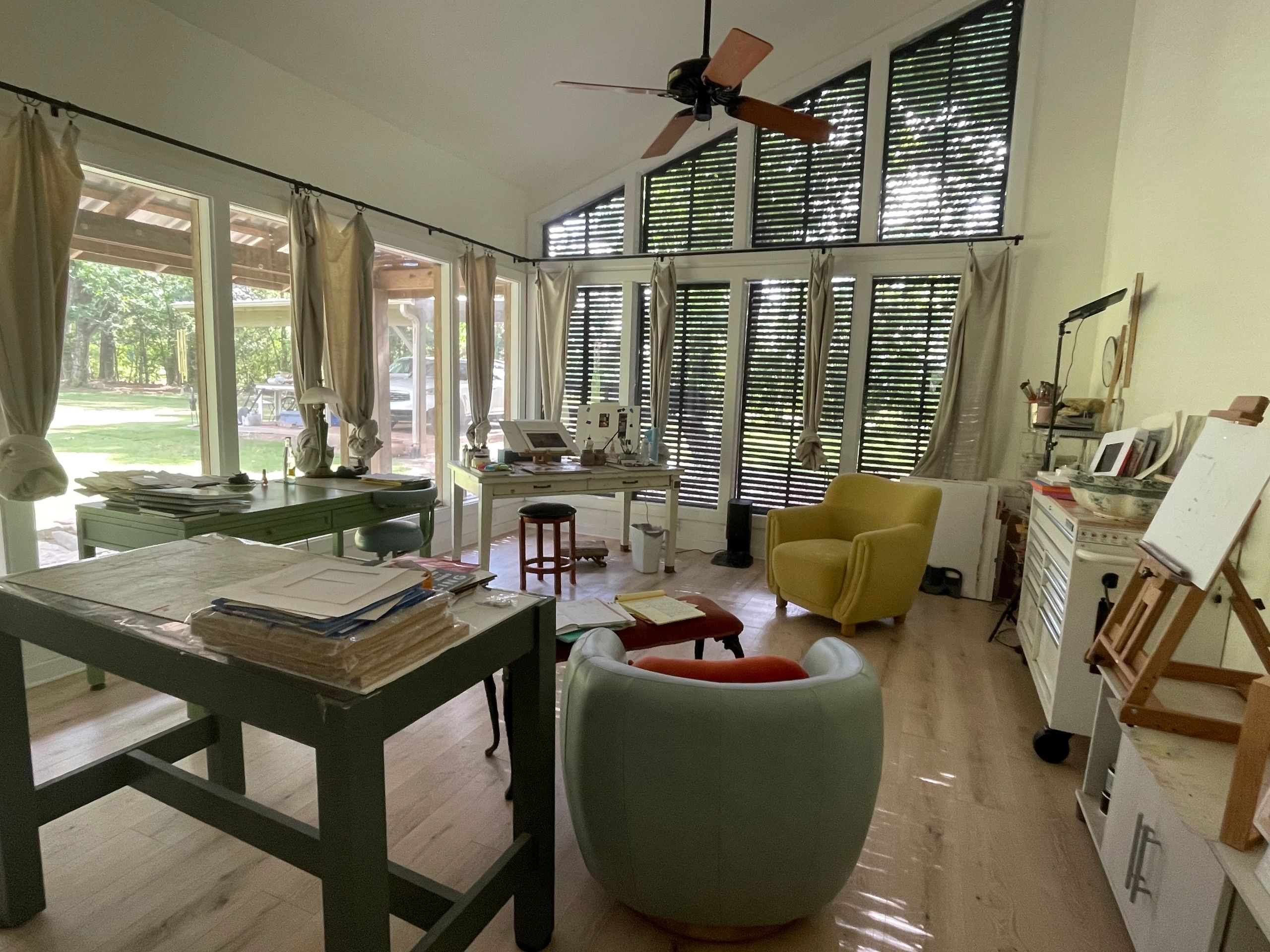 Bright art studio with large windows and colorful furniture.