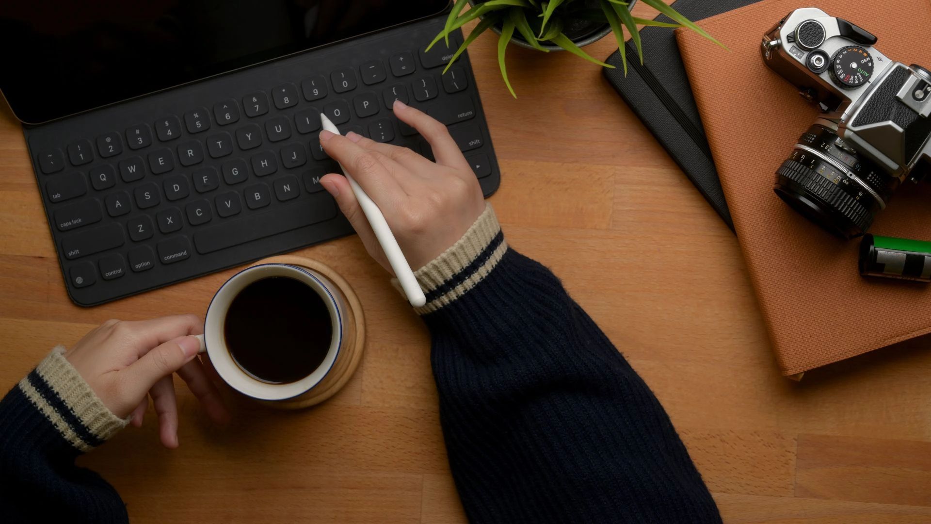 Person typing on computer with coffee and camera