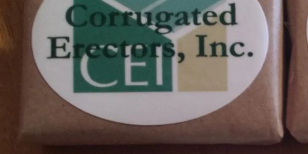 Logo of Corrugated Erectors, Inc. on a brown surface.