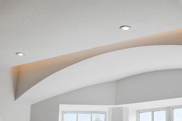 Curved white ceiling with recessed lighting and a window below.