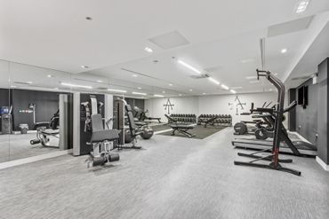 Modern gym with weight machines, treadmills, and mirrors on the walls.