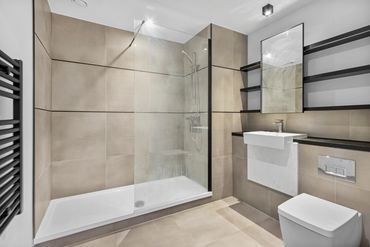 Modern bathroom with beige tiles, walk-in shower, and sleek fixtures.