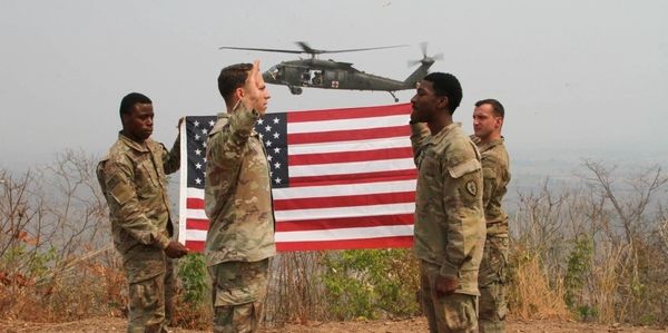 Nevada National Guard’s Soldier reenlisting in front of a helicopter and American flag