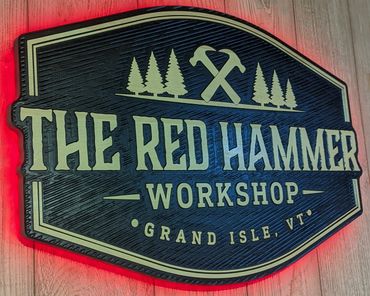 Wooden sign for The Red Hammer Workshop with red backlight.