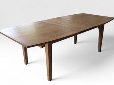 Modern wooden dining table with tapered legs and a warm finish.