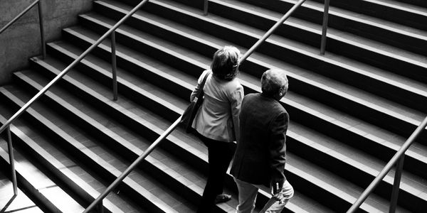 Two people walking up a staircase in black and white.