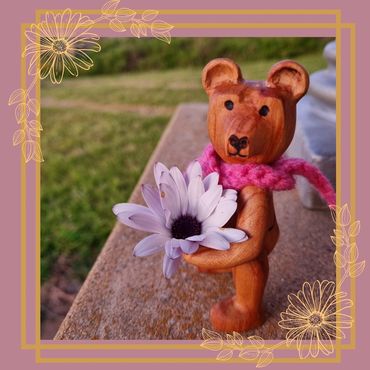 Hand carved wooden jointed bear holding a daisy 
