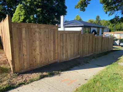 New wooden privacy fence along sidewalk near residential houses.