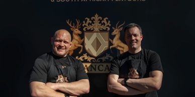 Two chefs proudly stand in front of a sign for Scottish and South African flavors.