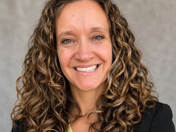 Smiling woman with curly hair and professional attire.