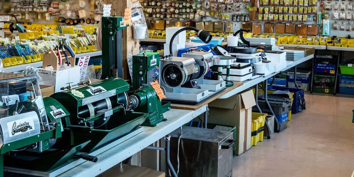 Lapidary, cabbing machines, pliers on tables and beading tools on peg boards in the distance.