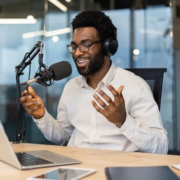Man recording podcast with microphone and laptop in modern office endorsing communication training and communication skills coaching by professional coaching services.