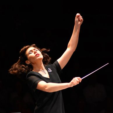 Female conductor leading an orchestra with passion.