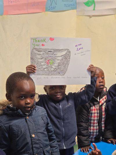Children holding a thank you poster in a classroom setting.