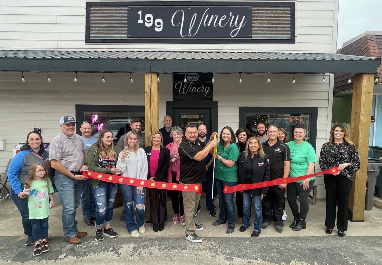 Group cuts red ribbon at winery opening event.