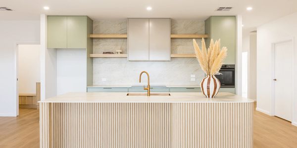 Modern kitchen with pastel green cabinets and a wooden island.