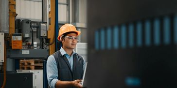 Factory worker wearing safety gear operating machinery.