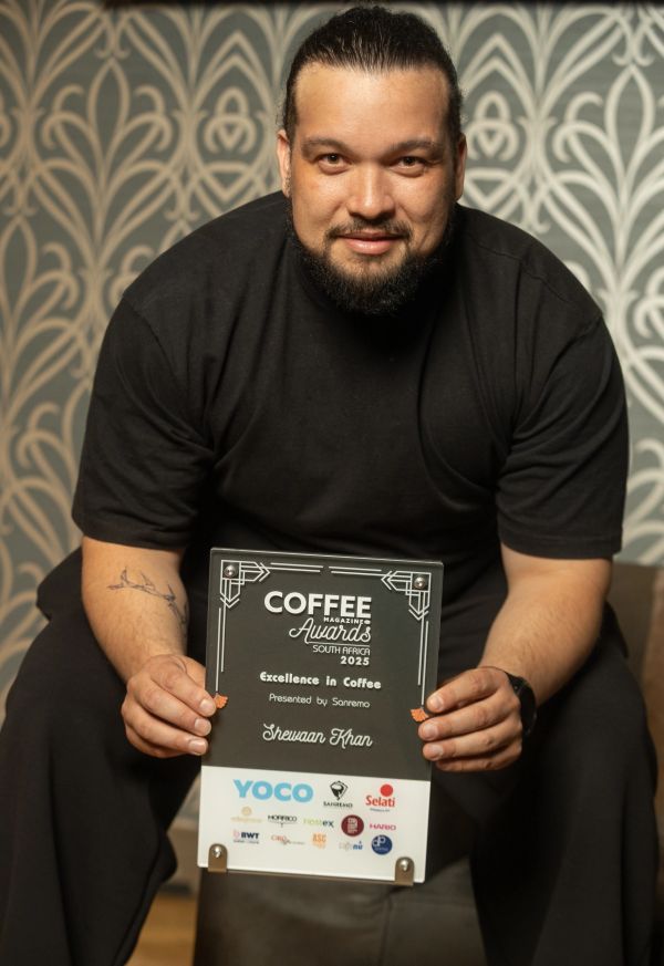 Man holding Coffee Magazine Award for Excellence in Coffee.