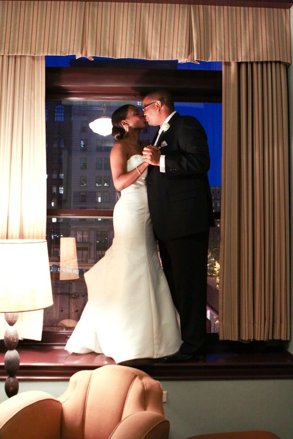 Bride and groom dancing in the window of their hotel suite