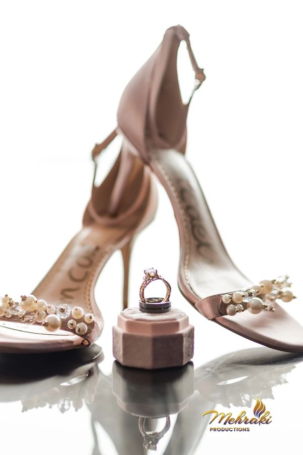 Elegant high heels with pearl embellishments and wedding rings on display.