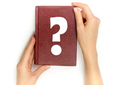 Hands holding a red book with a white question mark on the cover.