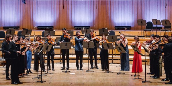 Orchestra playing string instruments on stage.