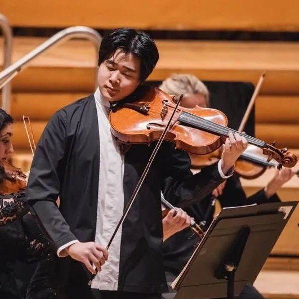 Musician intensely playing violin in an orchestra.