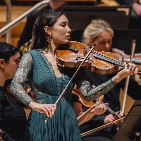 A focused violinist performs passionately in an orchestra.