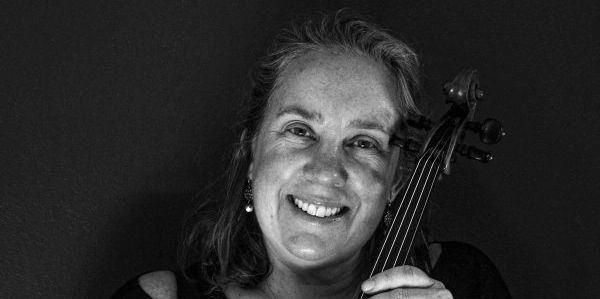 Black and white portrait of a smiling woman with a violin.