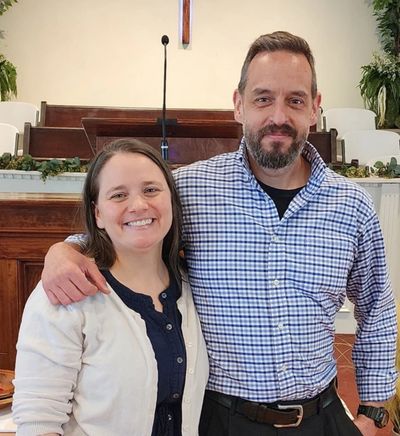 Smiling couple posing indoors with arm around each other.