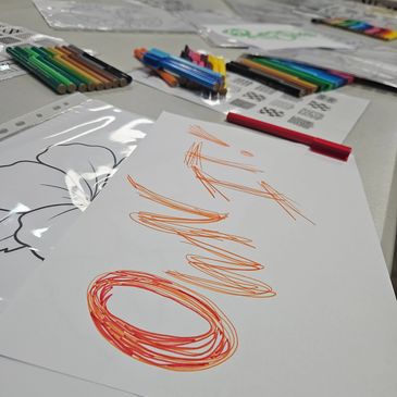 Art supplies and colorful drawings scattered on a table.