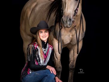 Smiling woman in cowboy hat poses with horse.