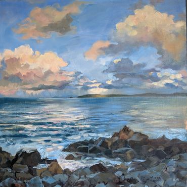 A serene coastal scene with rocky shore and cloudy sky at sunset.