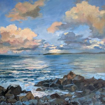 A serene coastal scene with rocky shore and cloudy sky at sunset.