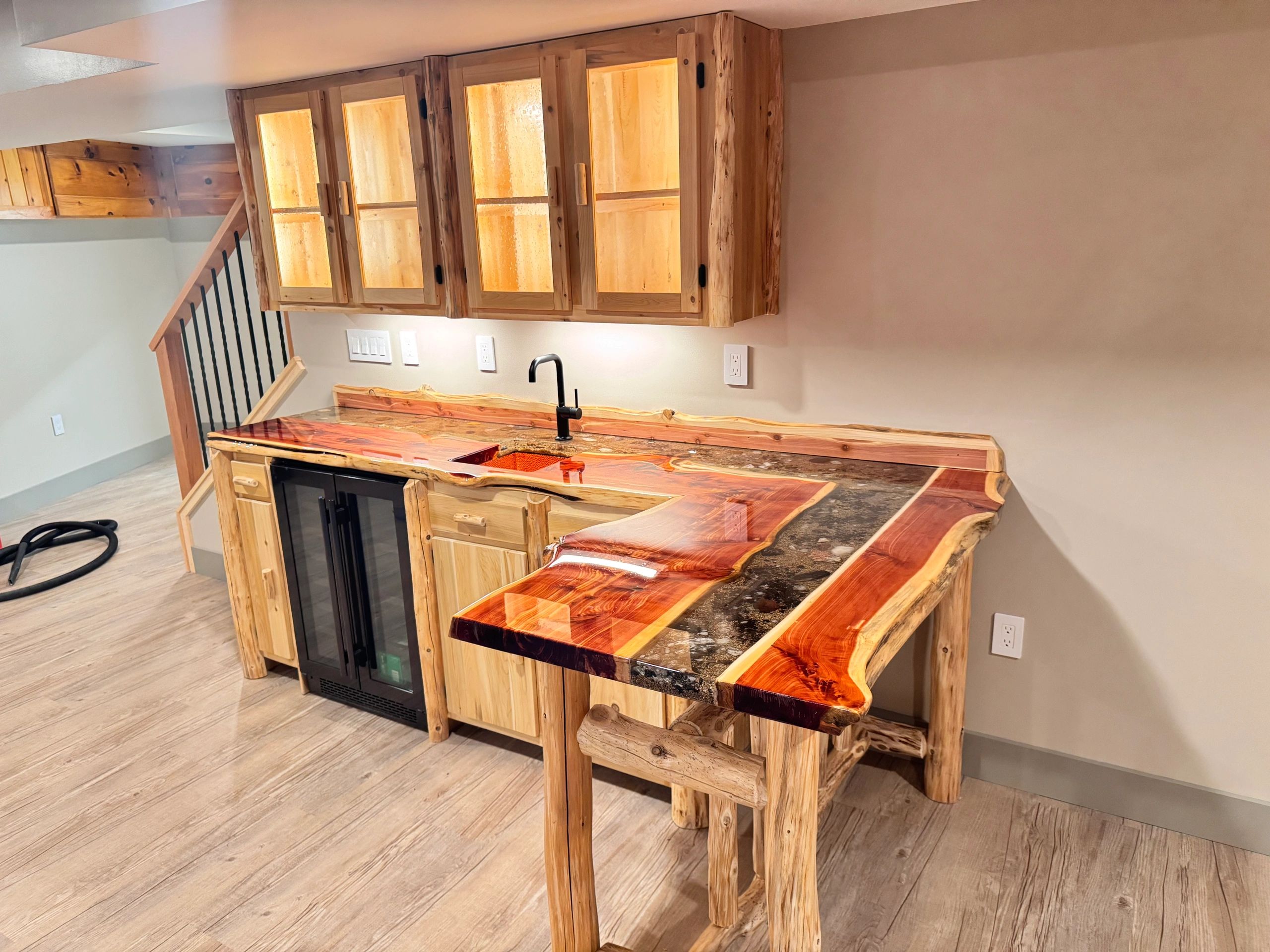 Rustic wooden kitchen counter with a unique epoxy resin countertop and matching cabinets.