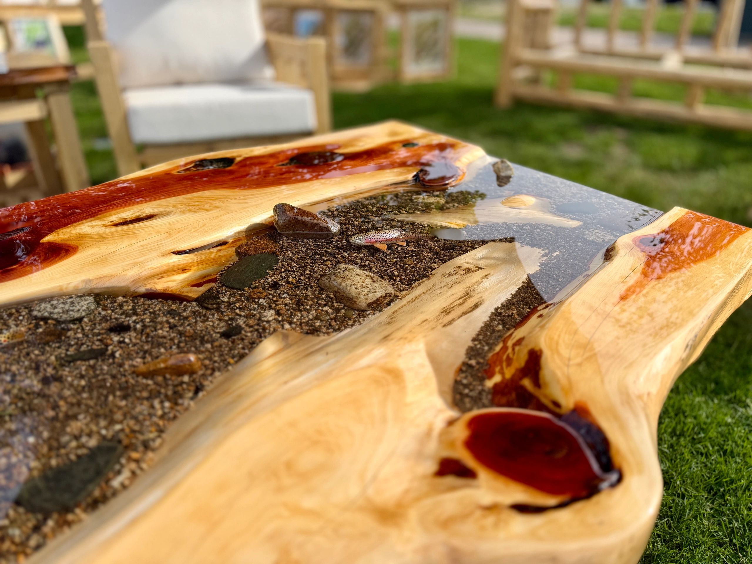 Artistic wooden table with embedded stones and resin water effect.