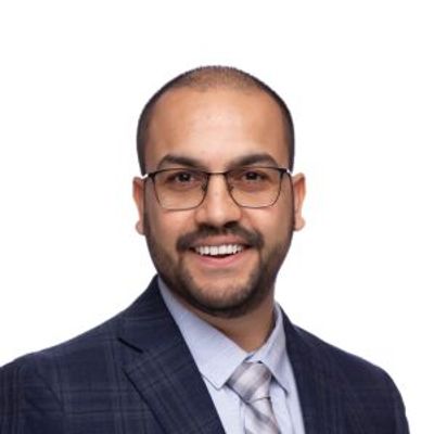 Smiling man in glasses and suit against a white background.