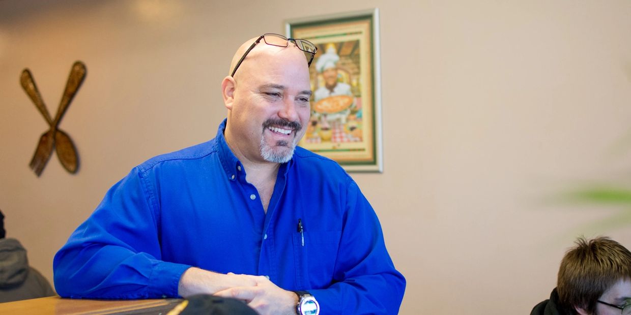 A man wearing blue shirt, smiling at camera