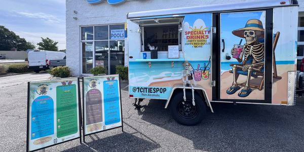 Colorful drink truck with skeleton art parked outside Innovative Spas store.