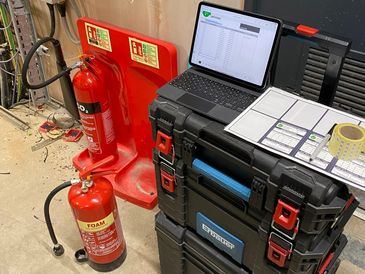 A safety inspection of foam fire extinguishers. Results being recorded on a laptop.