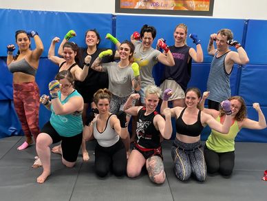 a group of women smile and flex after a women's class