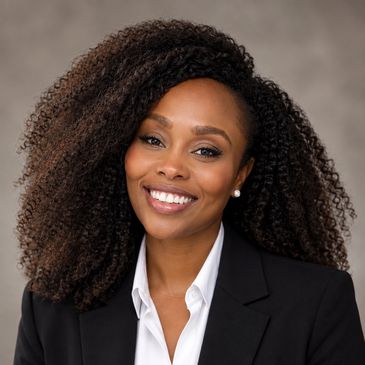 Smiling woman with curly hair in professional attire.
