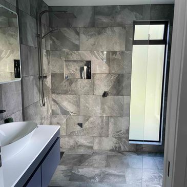 Beautiful modern fully tiled bathroom with rainfall shower