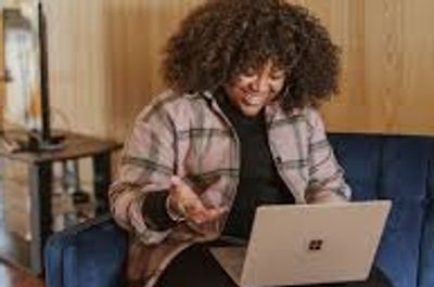 Woman smiling and gesturing at an open lap top